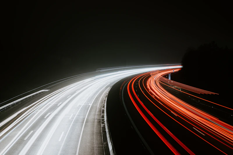 Lichtspuren von Autos auf einer Straße bei Nacht als Sinnbild für Geschwindigkeit